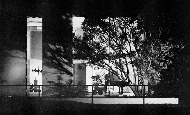 The Frank House, Case Study House #25, seen at night from the Rivo Alto Canal in 1962, with its tall front door lit at left and an olive tree in front of the glass walls