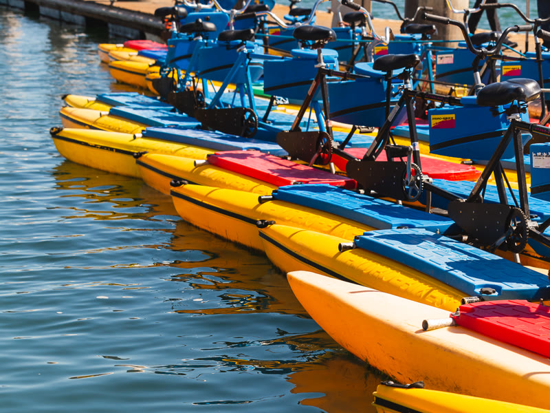 A row of yellow and blue hydrobike pontoons lined up at the dock on Alamitos Bay