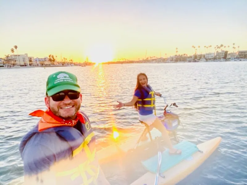 Two riders smiling on a hydrobike at golden hour