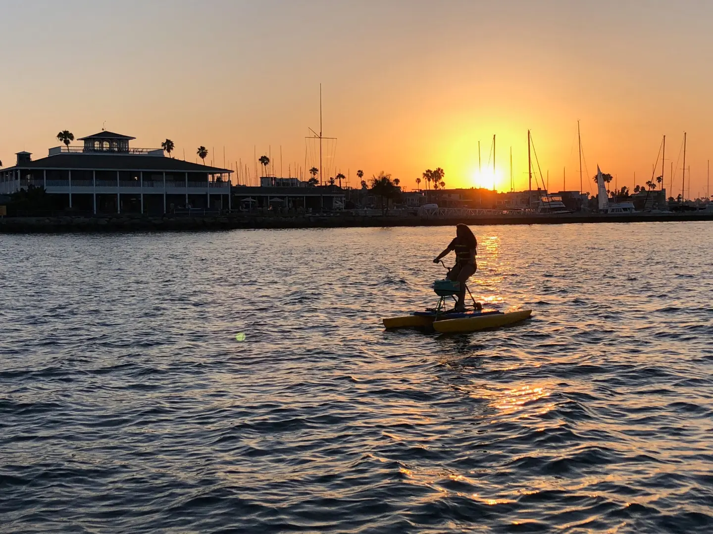 A rider on a hydrobike at sunset on Alamitos Bay