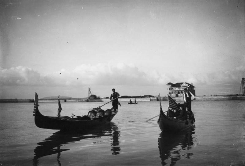 Black and white photo of two gondolas with gondoliers and passengers on the water off Naples