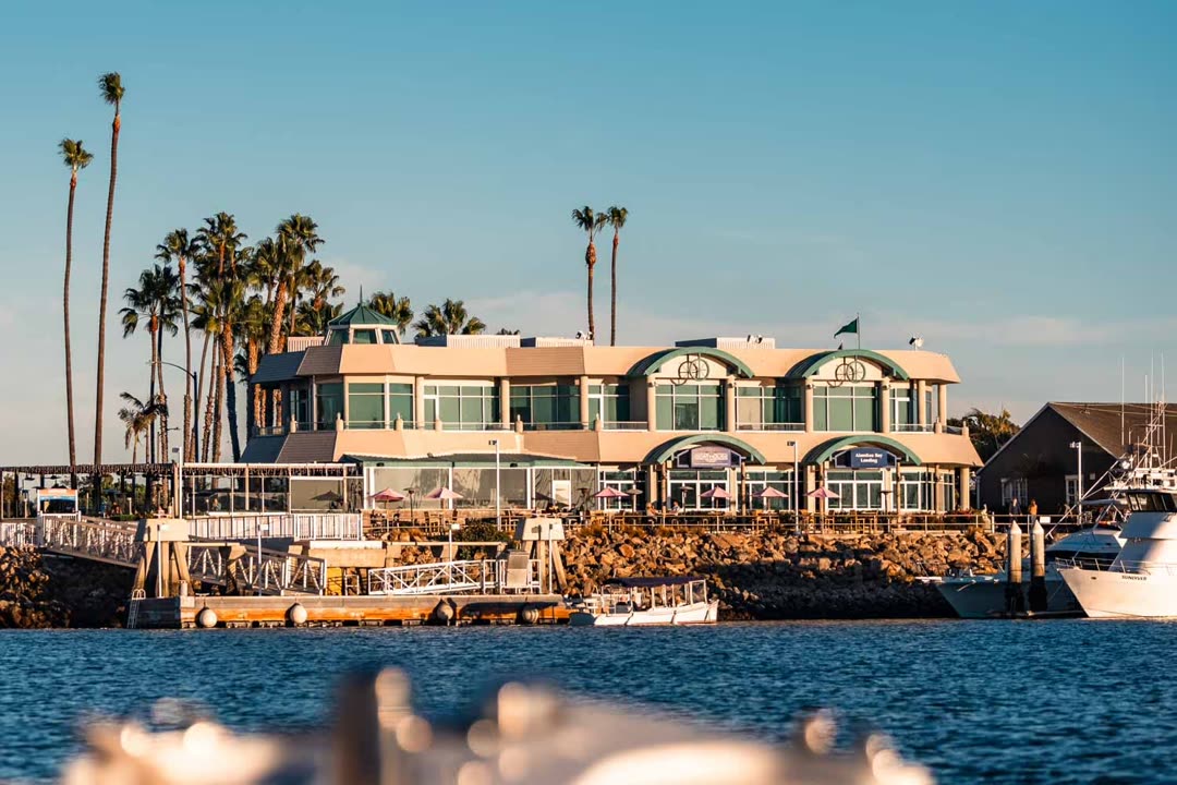 Boathouse on the Bay seen from the water at golden hour, with palm trees and boat docks in front