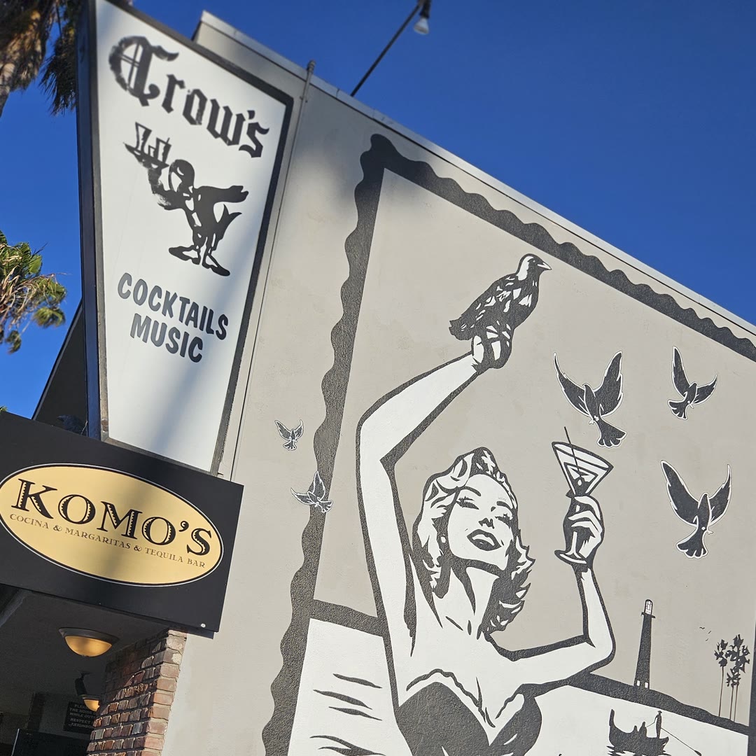 Crow's Cocktails on Second Street in Naples: the vertical Crow's sign and a large black and white pin-up mural on the white wall