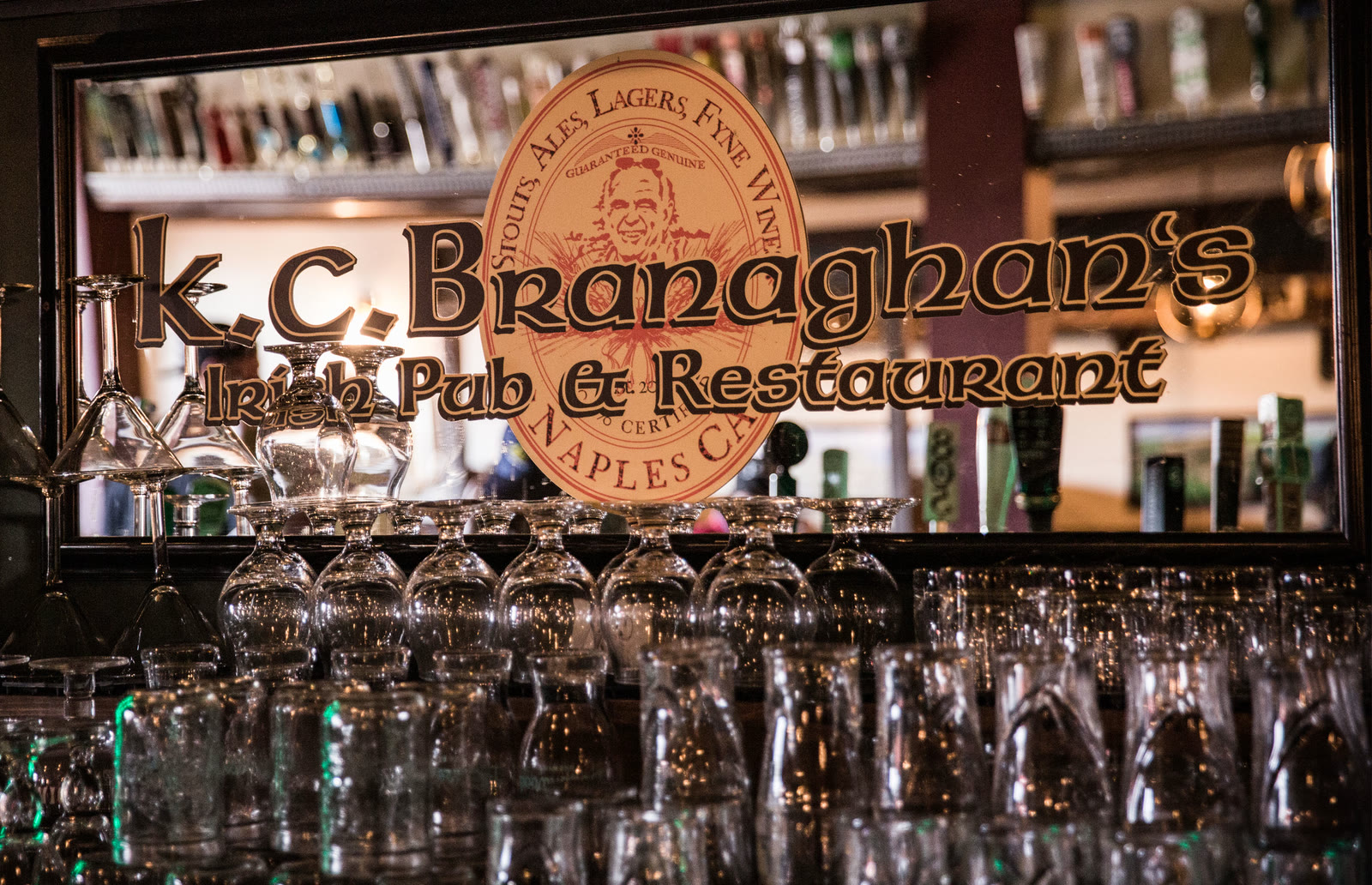 The bar at K.C. Branaghan's, with rows of glasses under the pub's carved logo sign