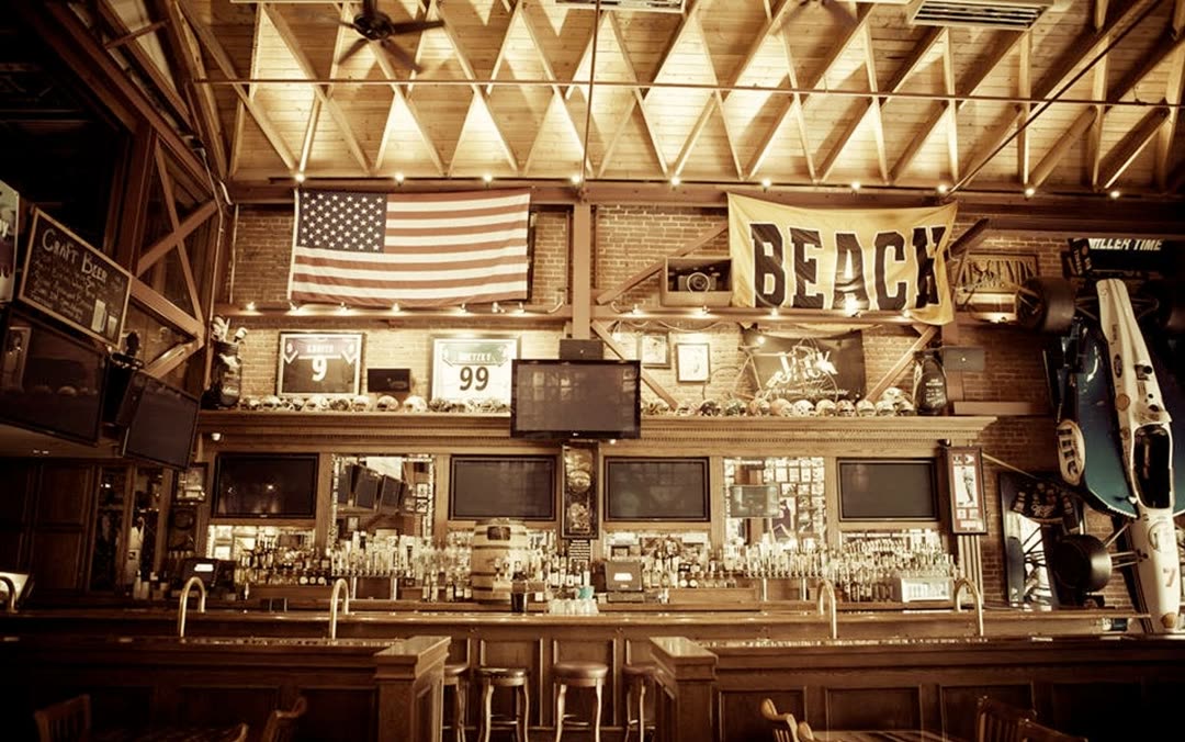 Sepia toned interior of Legends sports bar with an American flag, jerseys, helmets and an Indy car on display