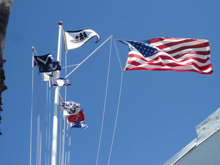 The Little Ships Fleet Yacht Club burgee, a black three-masted ship on white, flying beside the US flag