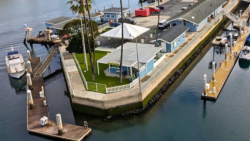 Aerial view of the Navy Yacht Club Long Beach clubhouse, lawn and docks on a point in the bay