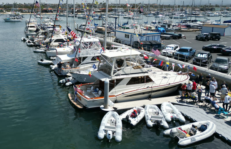 Aerial view of boats dressed in flags at a Seal Beach Yacht Club dock event in the Alamitos Bay Marina